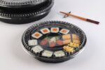 WL53 black sushi tray with clear plastic lid displaying assorted sushi rolls