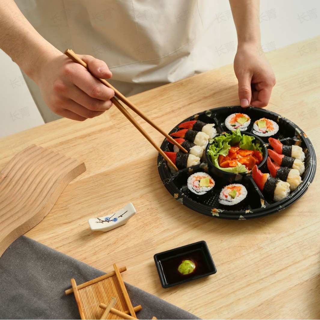 Black partition sushi tray served with assorted sushi rolls on a table for restaurant dining