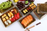 Assorted sushi containers with clear lids displaying sushi rolls, sashimi, and Japanese food items