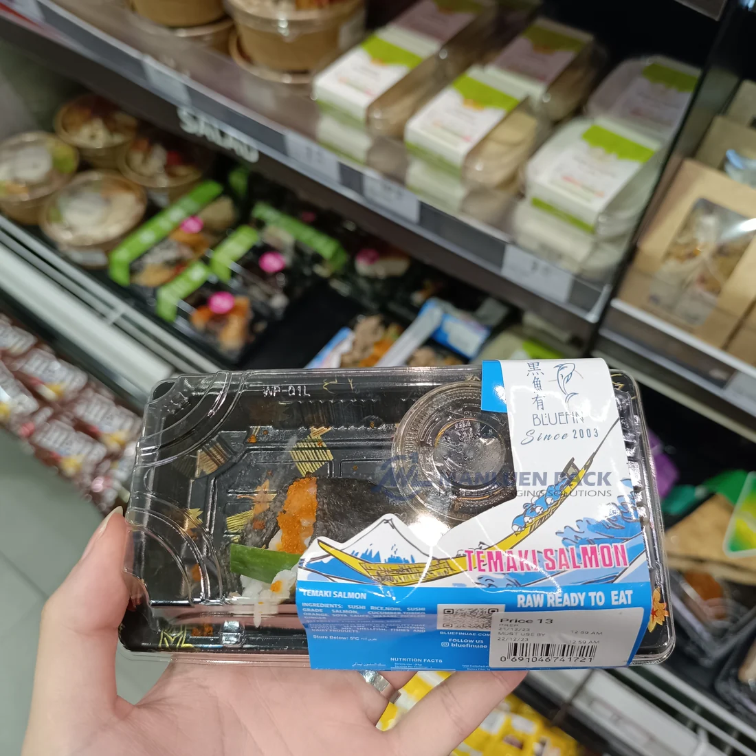 Packaged WL-00 sushi tray held by a shopper in a retail store