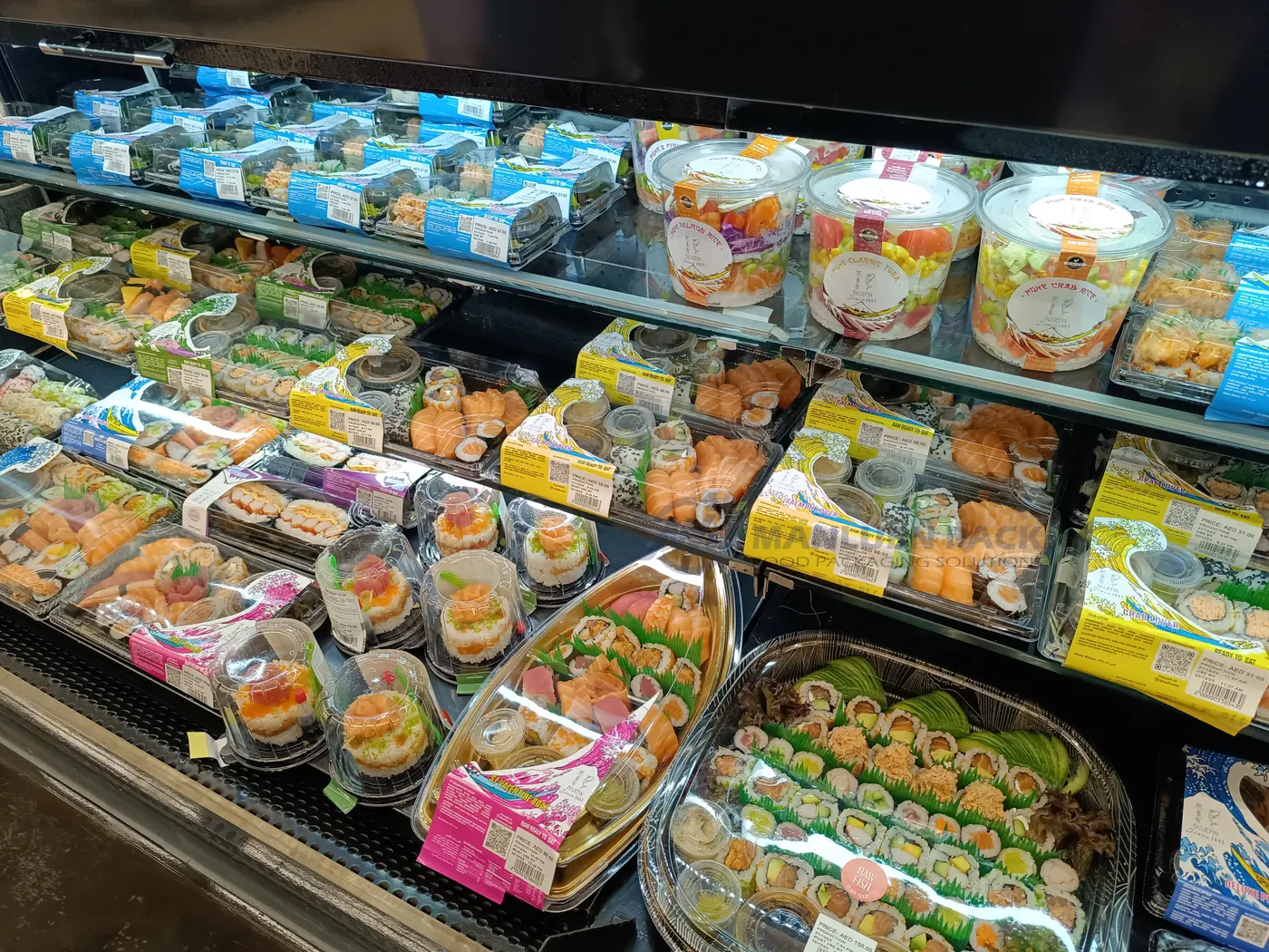 Large Sushi Party Trays in Retail Display | Manluen Pack Large square and round sushi platter trays arranged inside a prepared-food retail display case
