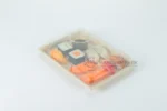 Covered WL-11 bagasse sushi tray with assorted sushi and sauce cup