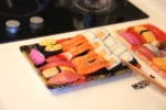 Open WL-11 sushi tray with assorted nigiri in a restaurant-style setting