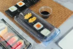 Covered WL-30B sushi tray with sushi rolls in a tabletop setting