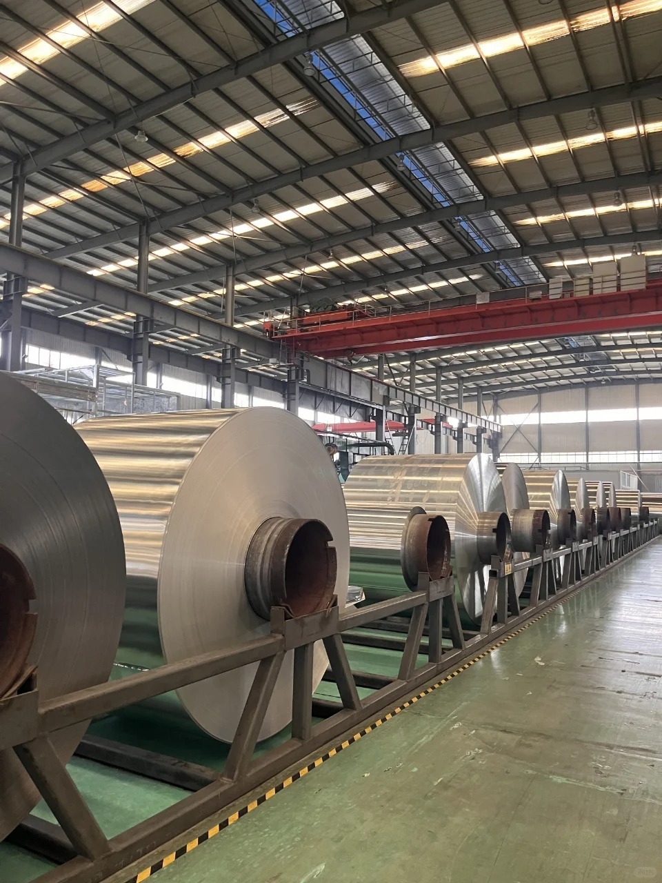 Is Aluminum Foil Safe for Food Packaging? A 2026 Buyer’s Guide 1 Large aluminum foil rolls stored on production stands inside an industrial manufacturing facility.