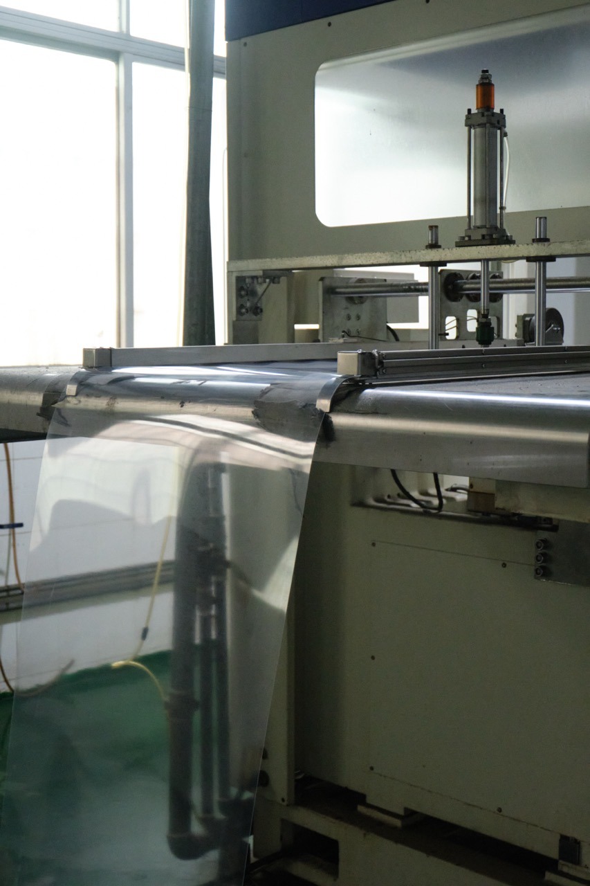 What Is Thermoforming? Process, Materials and Uses 5 Clear Plastic Sheet Fed Into Thermoforming Machine